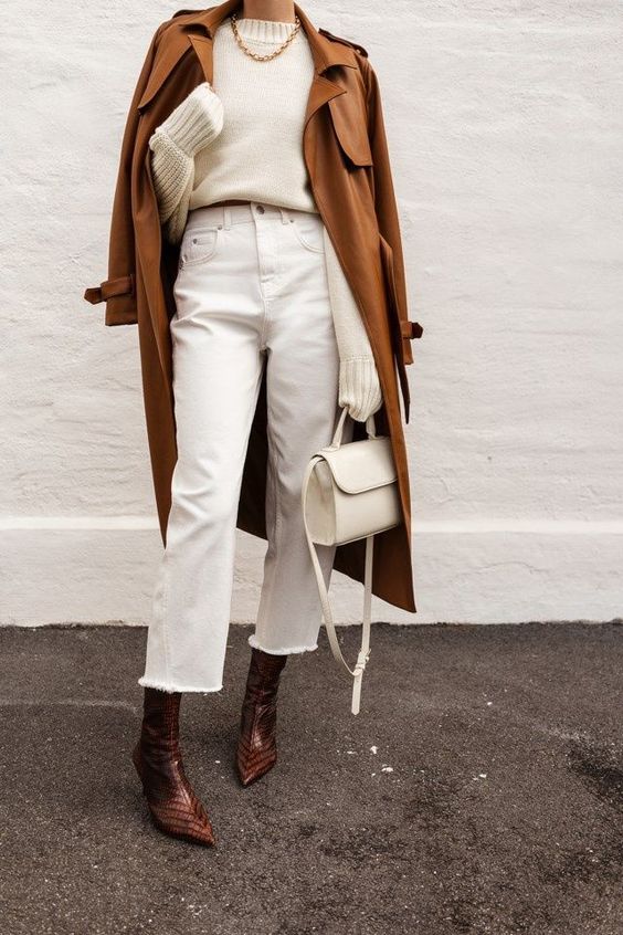 a chic fall outfit with a white jumper, white mom jeans, rust-colored boots, a brown trench and a white bag