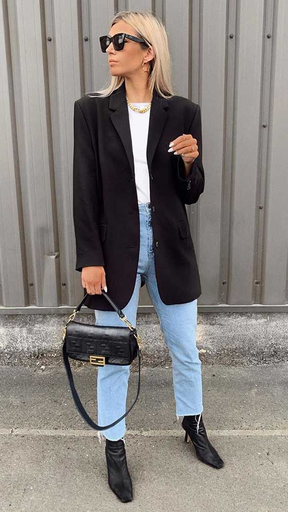 a chic office outfit with a white t-shirt, blue mom jeans, black boots, a black oversized blazer and a small black bag