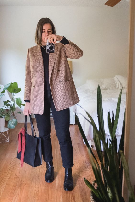 a fall office look with a black top, black mom jeans, black boots, a beige plaid blazer and a black tote