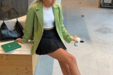 a girlish outfit with a white crop top, a grene blazer, a black pleated mini, white socks and black chunky loafers with chain
