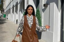 a stylish fall look with a printed shirt, a brown leather pinafore dress with gold buttons and a brown bag