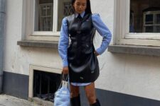 a trendy fall outfit with a blue shirt, a black overall leather dress, black knee boots and a blue bag