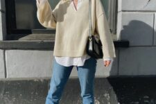 a white oversized shirt, a creamy V-neck sweater, blue mom jeans, black sneakers and a black bag for fall and winter