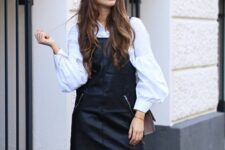 a white oversized shirt with puff sleeves, a black leather pinafore dress, a brown bag for a classy fall look