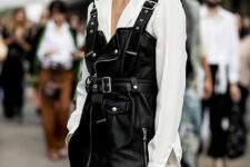a white shirt, a black leather overall dress in rock style and a metallic clutch compose a lovely rock look