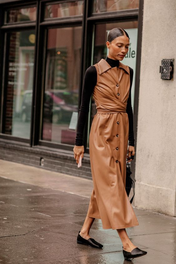 an elegant and laconic fall look with a brown turtleneck, a camel leather overall midi dress, black shoes and a black bag
