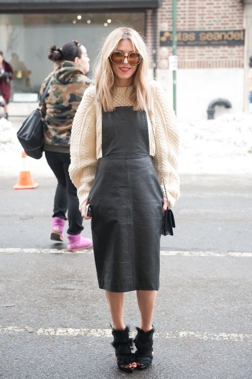 an oversized white patterned sweater, a black leather overall dress, black boots and a black bag for winter