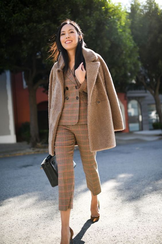 a brown plaid pantsuit with cropped pants, a brown faux fur coat, a black bag and brown shoes