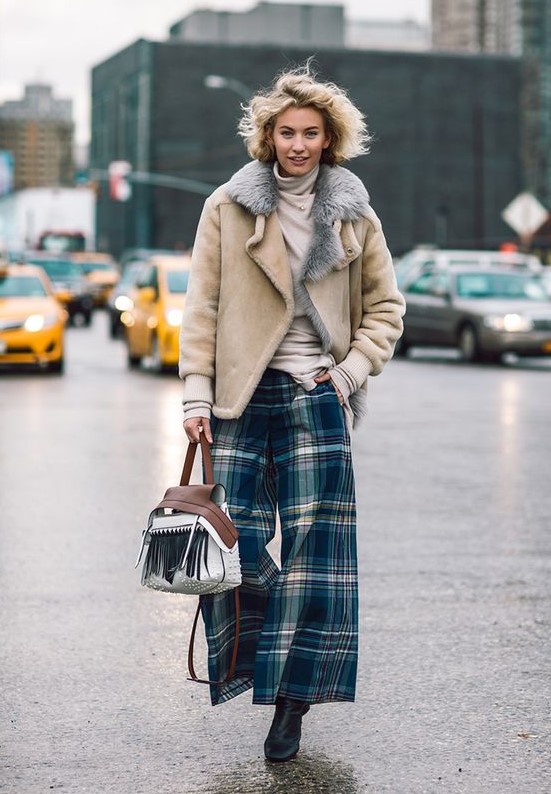 a winter look with a neutral turtleneck, plaid wideleg pants, black boots, a neutral shearling coat and a fringe bag