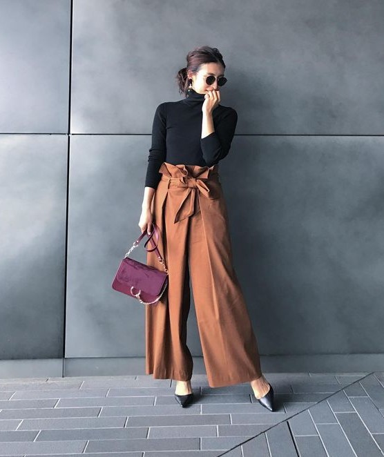 a black turtleneck, rust-colored high waisted wideleg pants, black shoes and a burgundy bag