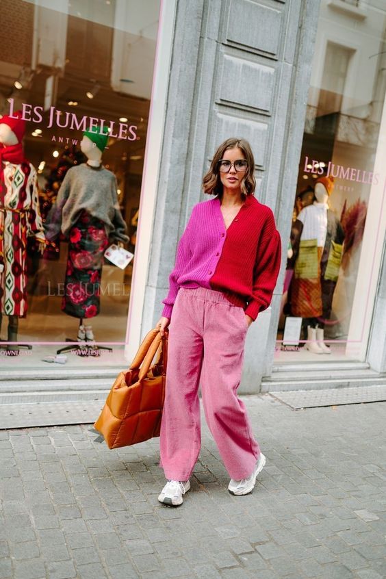a catchy and bold Thanksgiving outfit with pink velvet pants, trainers, a pink and red cardigan and a quilted bag
