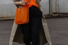 22 a comfortable casual look with an orange jumper, black trousers, a neutral trench, an orange tote and white sneakers
