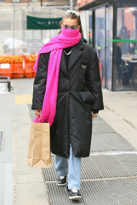 Bella Hadid wearing a black puffer coat, bleached jeans and black sneakers, a hot pink chunky scarf are a cool combo for winter