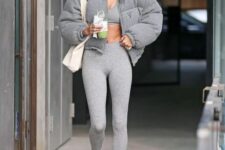 Hailey Bieber wearing a total grey look with a crop top, leggings, white socks and sneakers, a matching cropped puffer and a white tote
