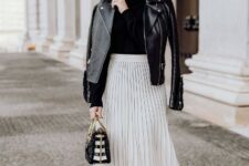 With sunglasses, golden rounded earrings, black leather jacket, black leather heeled mid calf boots and black and white striped bag