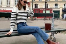 a Breton stripe sweater, blue jeans, burgundy block heel boots and a burgundy bucket bag