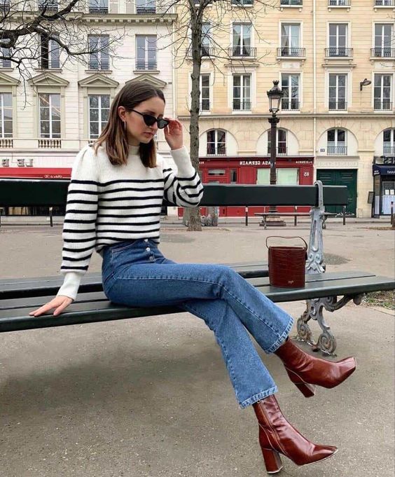 a Breton stripe sweater, blue jeans, burgundy block heel boots and a burgundy bucket bag