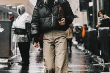 a black sweater, grey wideleg pants, burgundy leather boots, a croppe dblack puffer jacket and a clutch