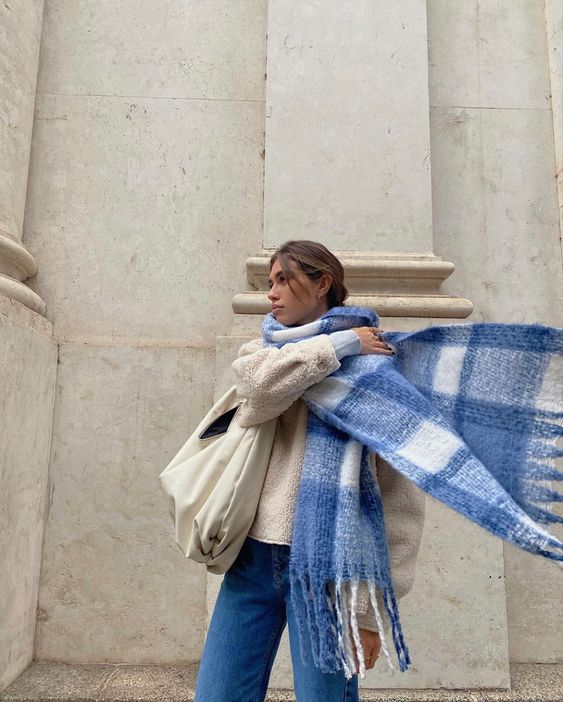 a blue and white winter outfit with blue jeans, a creamy plush jacket and a large bag, a blue plaid oversized scarf