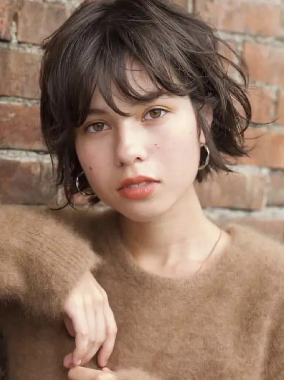 a brown messy and layered boy bob with bangs is a chic and relaxed idea to pull off