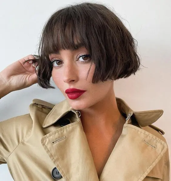 A chic dark brunette ear length bob with a classic fringe and messy waves looks relaxed, cute and refined