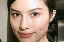 a clean girl makeup with a glossy nude lip, a subtle touch of neutral eyeshadow, pink blush and dewy skin