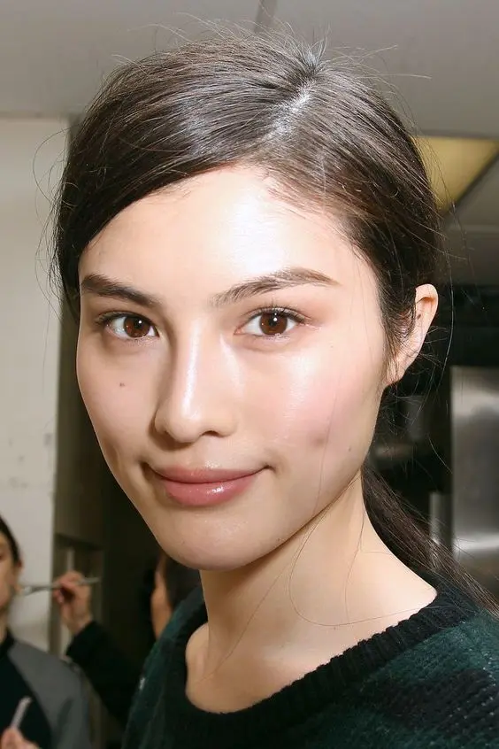 a clean girl makeup with a glossy nude lip, a subtle touch of neutral eyeshadow, pink blush and dewy skin