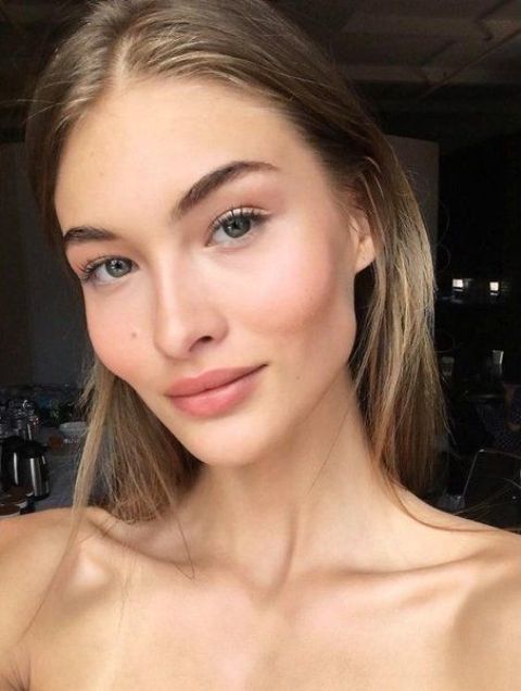 a clean girl makeup with a matte nude lip, a touch of pink blush and accented eyebrows is cool