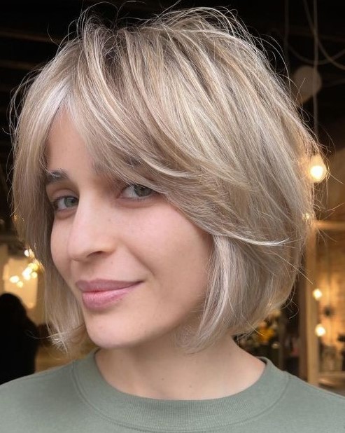 A cold blonde feathered chin length bob with curtain bangs is a very fresh and modern solution that brings movement