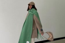 a comfy and chic winter look with a taupe oversized blazer and a cap, white jeans and sneakers, an oversized green scarf