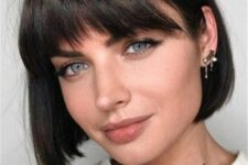a dark brunette, almost black boy bob haircut with wavy outgrown bangs is a stylish idea to try right now