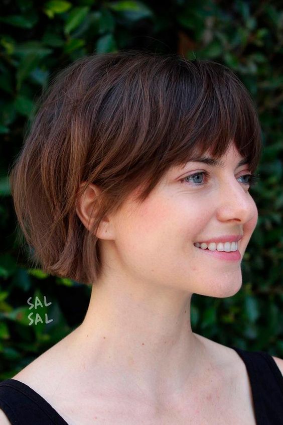 A dark brunette jaw length bob with caramel balayage and layered bangs is a catchy idea to rock right now