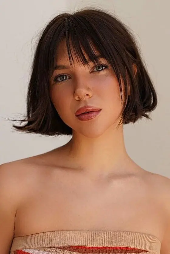 A dark brunette jaw line bob with face framing layers and wispy bangs and a bit of volume is a great idea for any season
