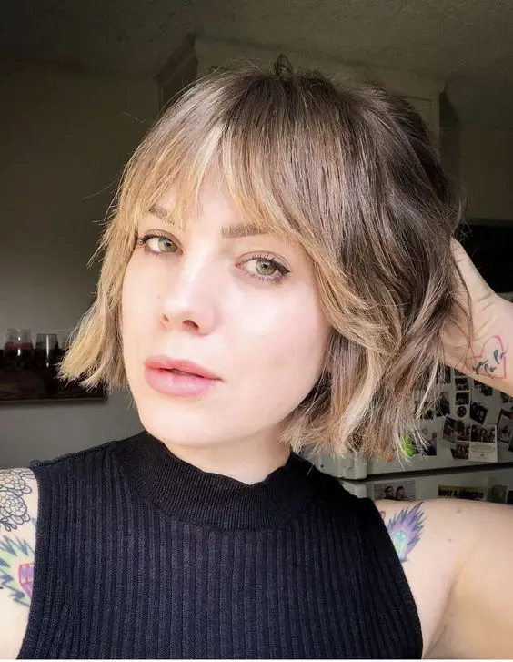 a delicate jaw-length bob with blonde balayage and wispy bangs plus a bit of waves is a relaxed and cool idea