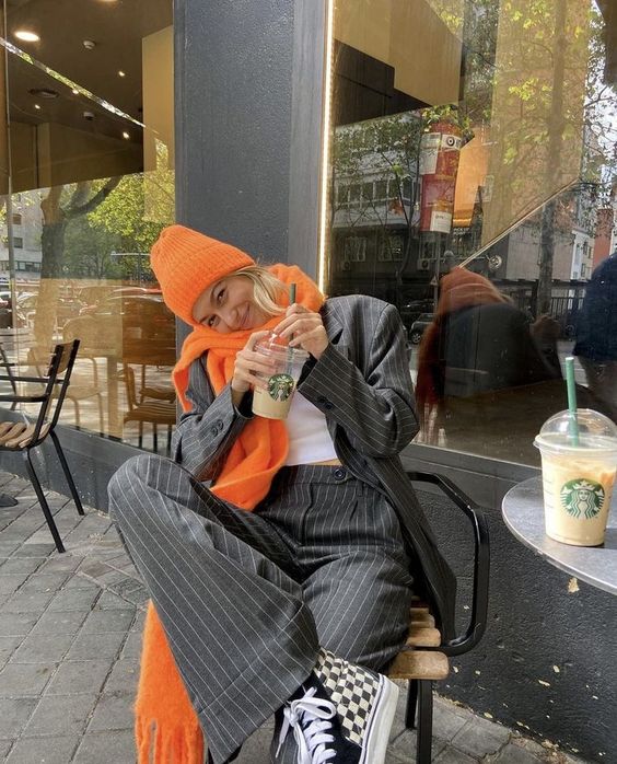 a grey thin stripe pantsuit, a white top and black and white sneakers, a bold orange scarf and a beanie are amazing for a cold day