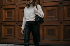 a grey turtleneck and a matching cardigan tucked into black leather pants, beige Chelsea boots and a black bag