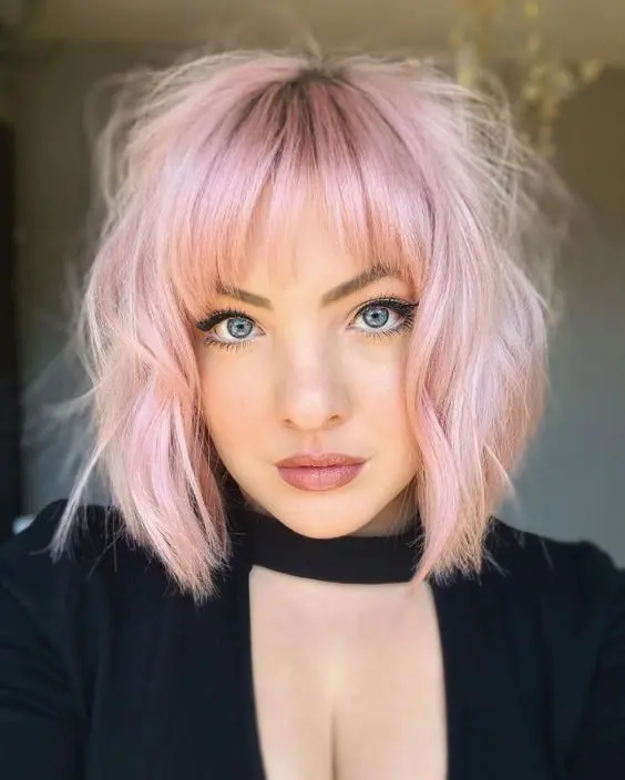 a lovely shaggy pastel pink short bob with wispy bangs looks really chic and glam