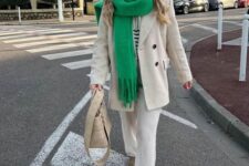 a neutral outfit with a striped sweater, neutral trousers, an oversized neutral blazer, taupe ugg boots, a neutral bag and a bold green scarf