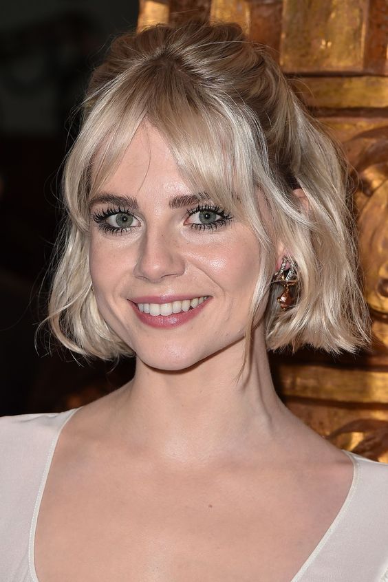 a platinum blonde chin-length bob with curtain bangs and waves styled as a half updo is a catchy idea