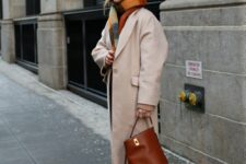 a refined look wh a tan coat, white trousers, brown boots, a bold plaid scarf and a brown bucket bag are geat for winter