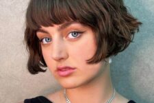 a short brunette bob with a classic fringe and messy waves is a retro-inspired and chic hairstyle