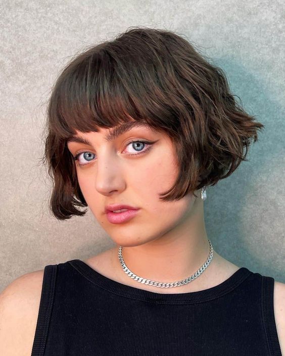 A short brunette bob with a classic fringe and messy waves is a retro inspired and chic hairstyle