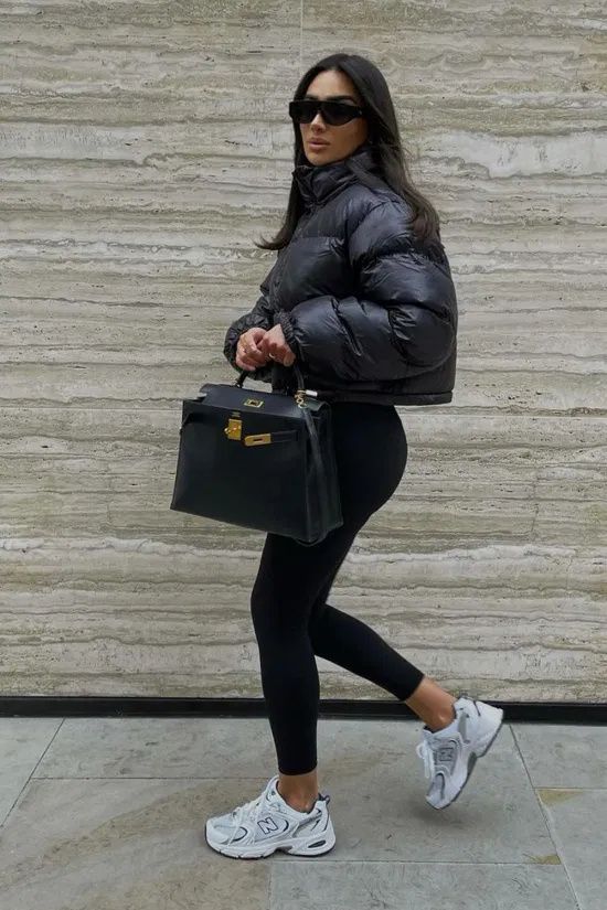 a simple black winter look with leggings, white trainers, a black cropped puffer jacket and a black tote