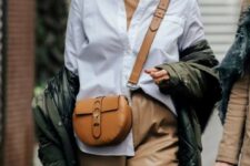 a tan turtleneck, a white shirt, tan leather trousers, a camel bag, a green puffer jacket and statement earrings