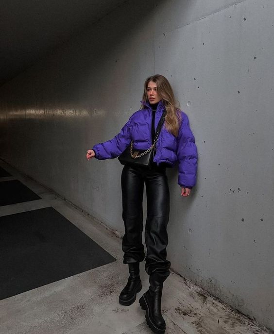 a total black look accented with a bold touch, with leather pants, boots, a turtleneck and a bag plus a bold purple cropped puffer jacket