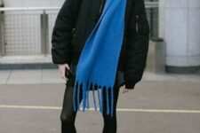 a total black look with a mini skirt, tights, combat boots, a bomber jacket and a bold blue scarf for an accent