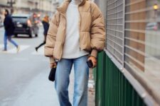 a white sweater, blue jeans, black combat boots, a beige cropped puffer jacket and a black bag