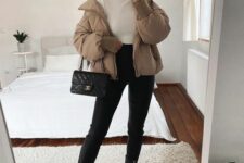 a white turtleneck, black jeans, black leather boots, a beige puffer jacket, a black bag for an elegant winter look