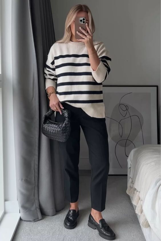 a work outfit with a Breton stripe sweater, black pants, black loafers and a black woven bag