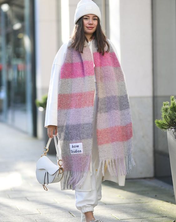 an all-white look with a sweatshirt and sweatpants, trainers and a small saddle bag, a beanie and a gorgeous bold striped scarf